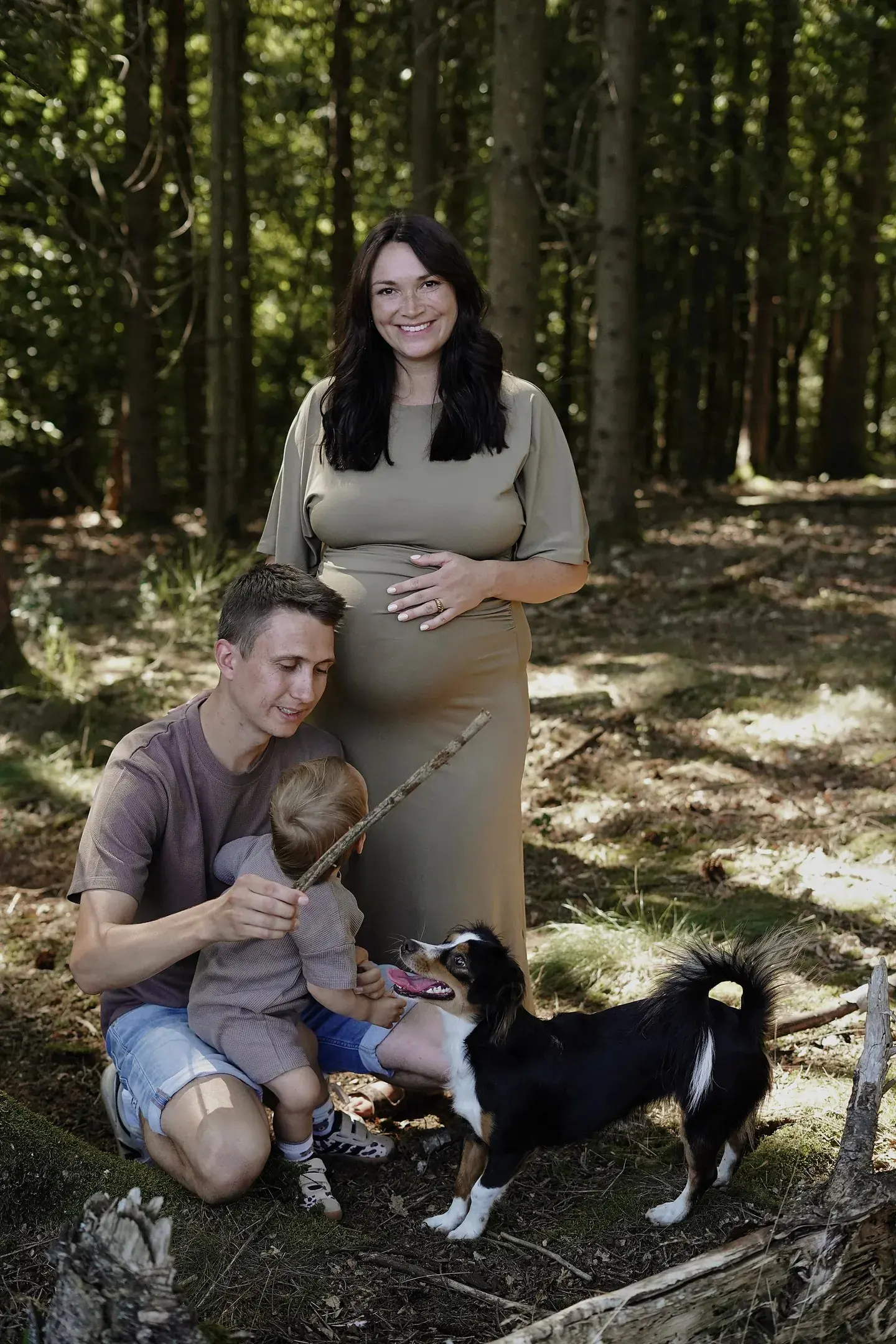 Familie im Wald spielt mit ihrem Hund